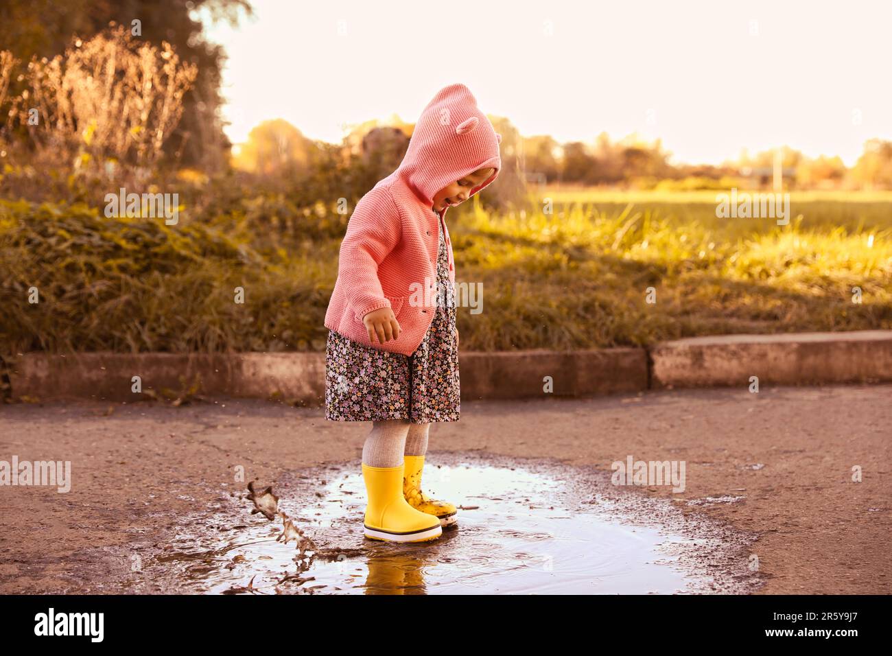 Little girl wearing rubber boots walking in puddle outdoors Stock Photo ...