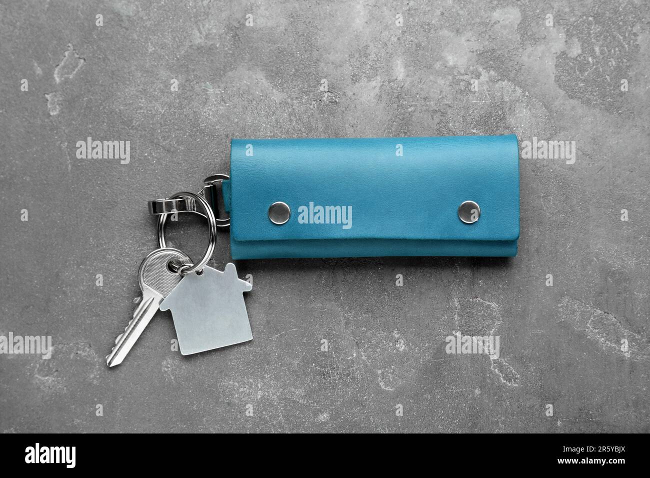 Leather case with key on grey textured table, top view. Stock Photo