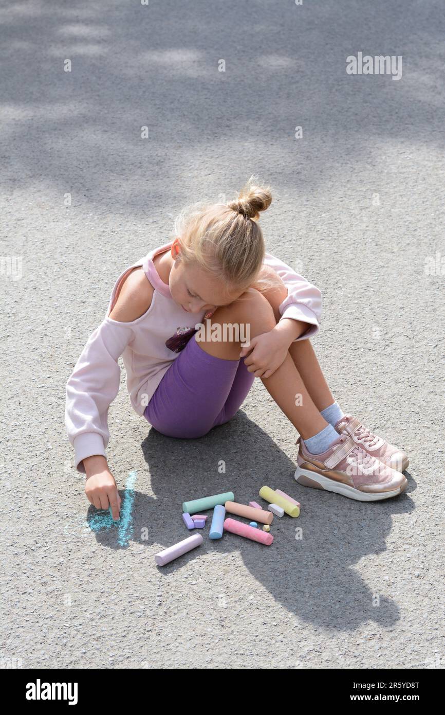 Little child drawing flower with chalk on asphalt Stock Photo - Alamy