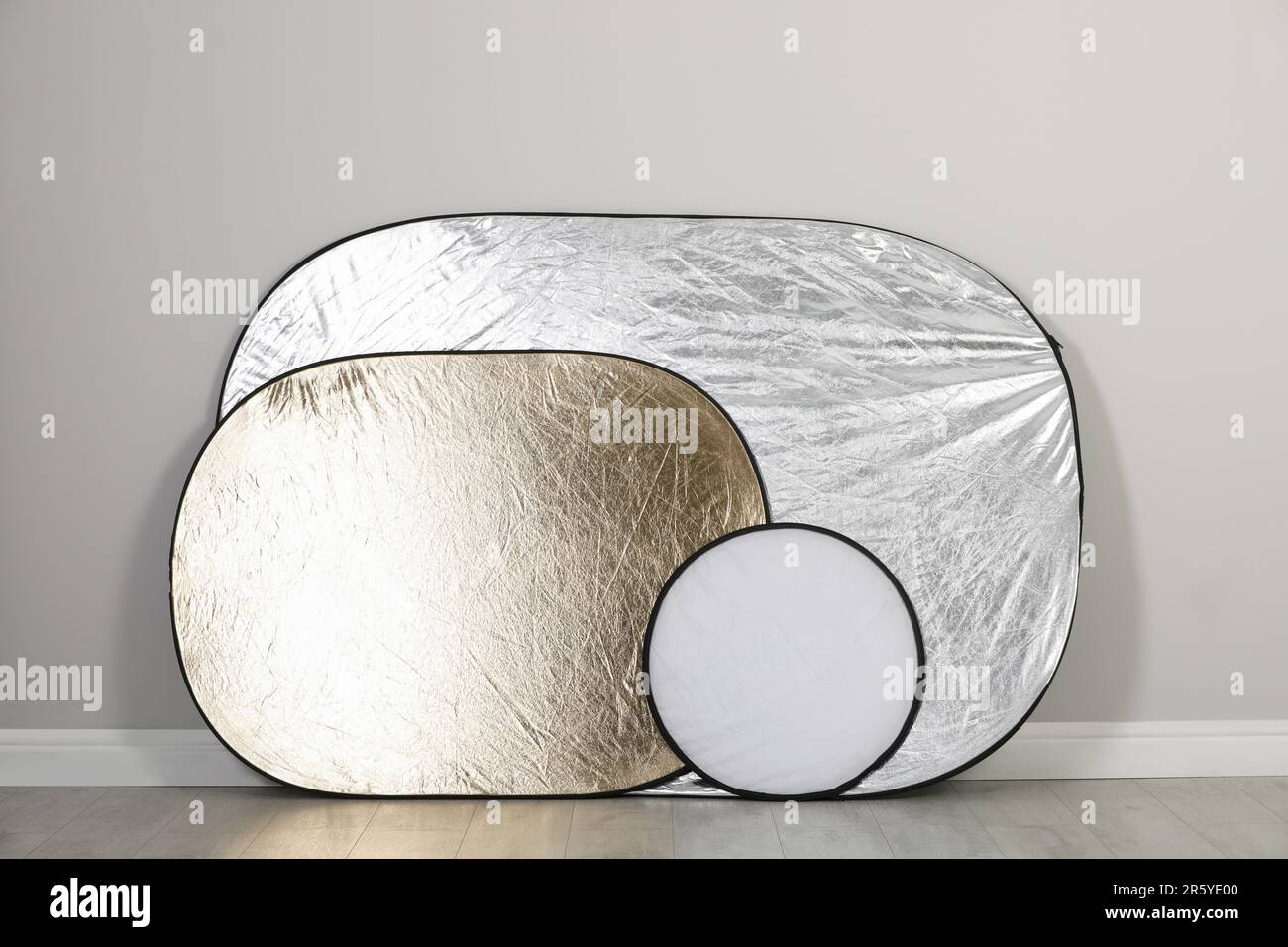 Studio reflectors near grey wall in room. Professional photographer's