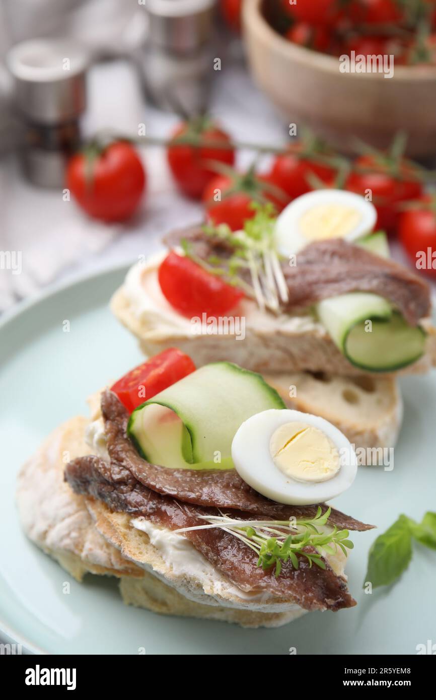 Delicious bruschettas with anchovies, tomato, cucumber, egg and cream cheese on plate, closeup Stock Photo