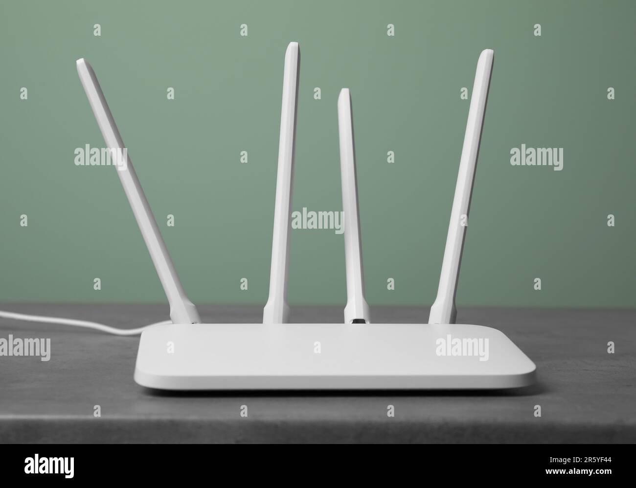 New modern Wi-Fi router on grey table near green wall Stock Photo - Alamy