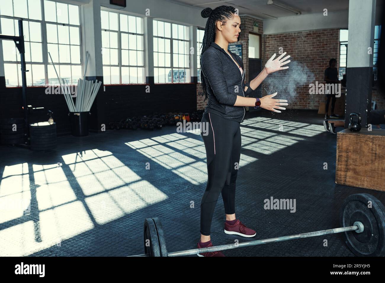 Getting ready to lift some weights. a young woman dusting her hands with chalk before lifting
