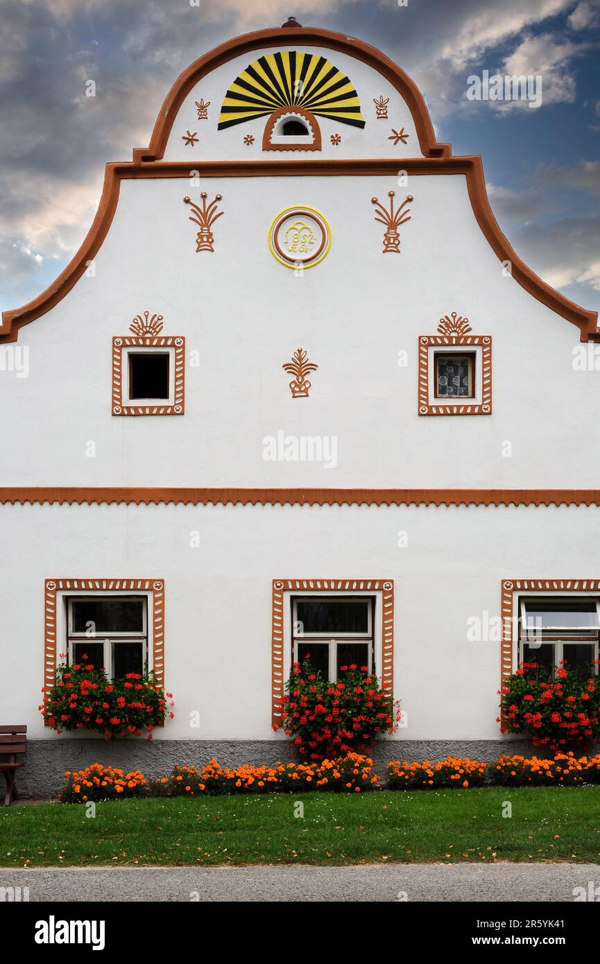 Stucco decoration on facade of house indicates the owner’s profession of farmer as well as displaying the date the house was built, 1852, and the owner’s initials. In Holašovice, South Bohemia, Czech Republic or Czechia, a well-preserved example of a traditional Central European village with many farmers’ houses rebuilt in the 1800s AD in a style known as South Bohemian Folk Baroque, Rural Baroque or Rustic Baroque. Stock Photo
