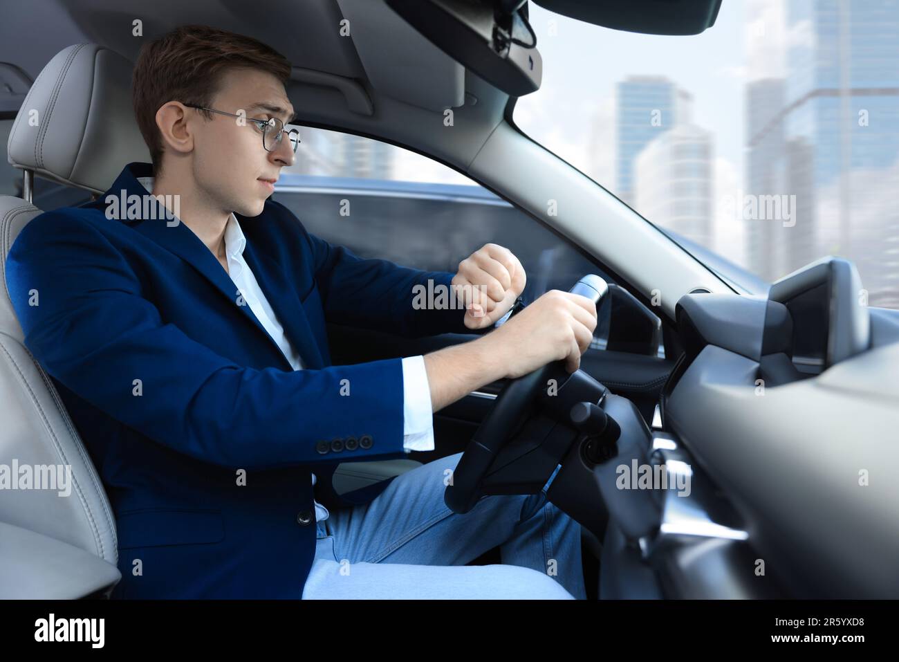 Young man checking time in car. Being late Stock Photo - Alamy
