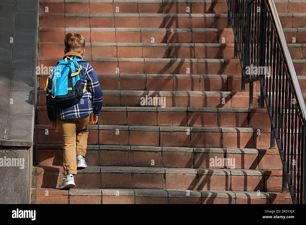 Little boy with backpack going up stairs to school, back view Stock ...