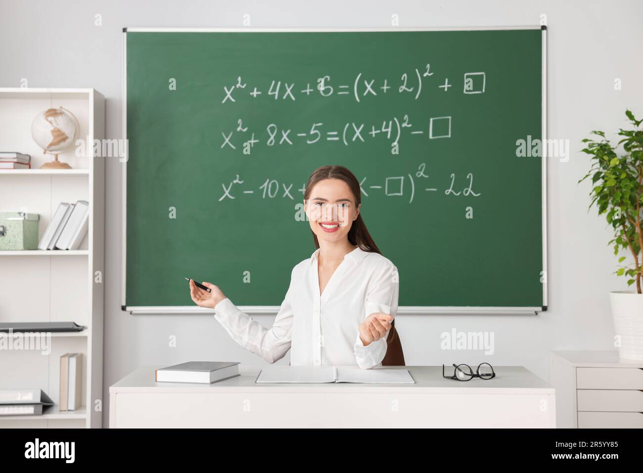 Young math’s teacher giving lesson at table in classroom Stock Photo ...