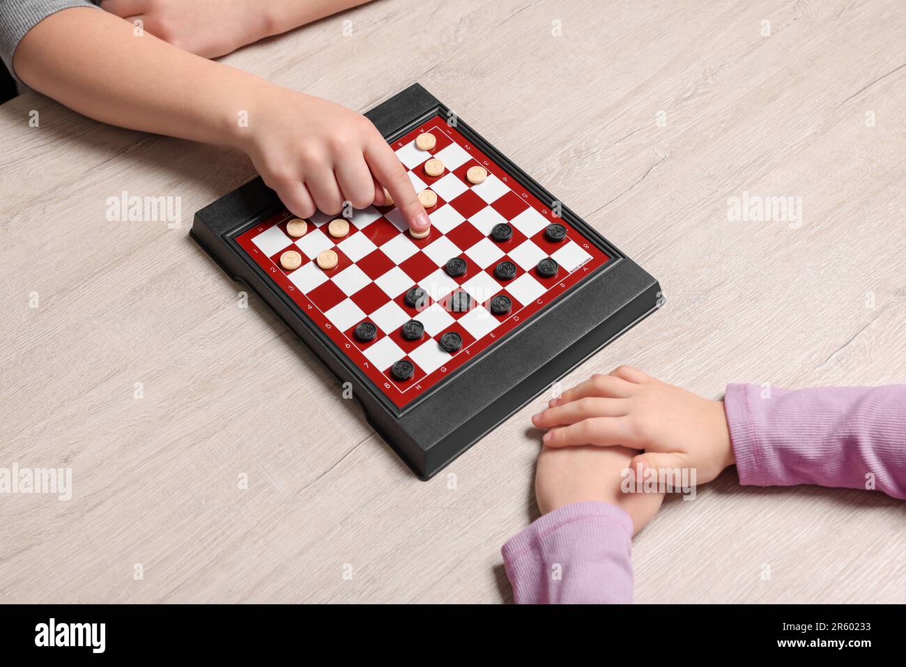 Children playing checkers at light wooden table, closeup Stock Photo ...