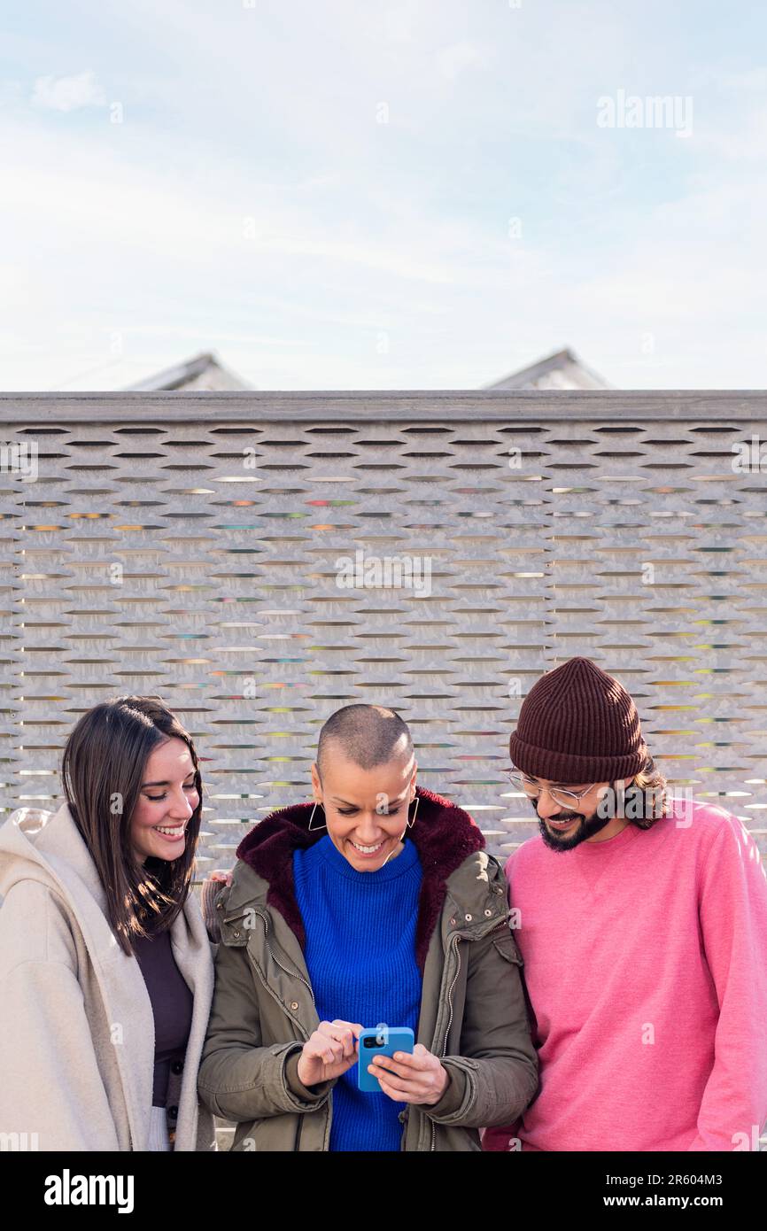 three young friends smiling happy using a phone Stock Photo