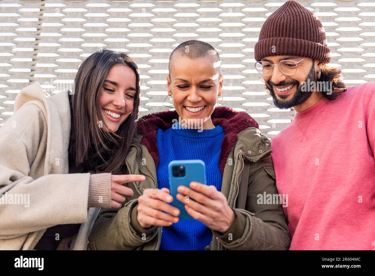 three young friends smiling happy using a phone Stock Photo