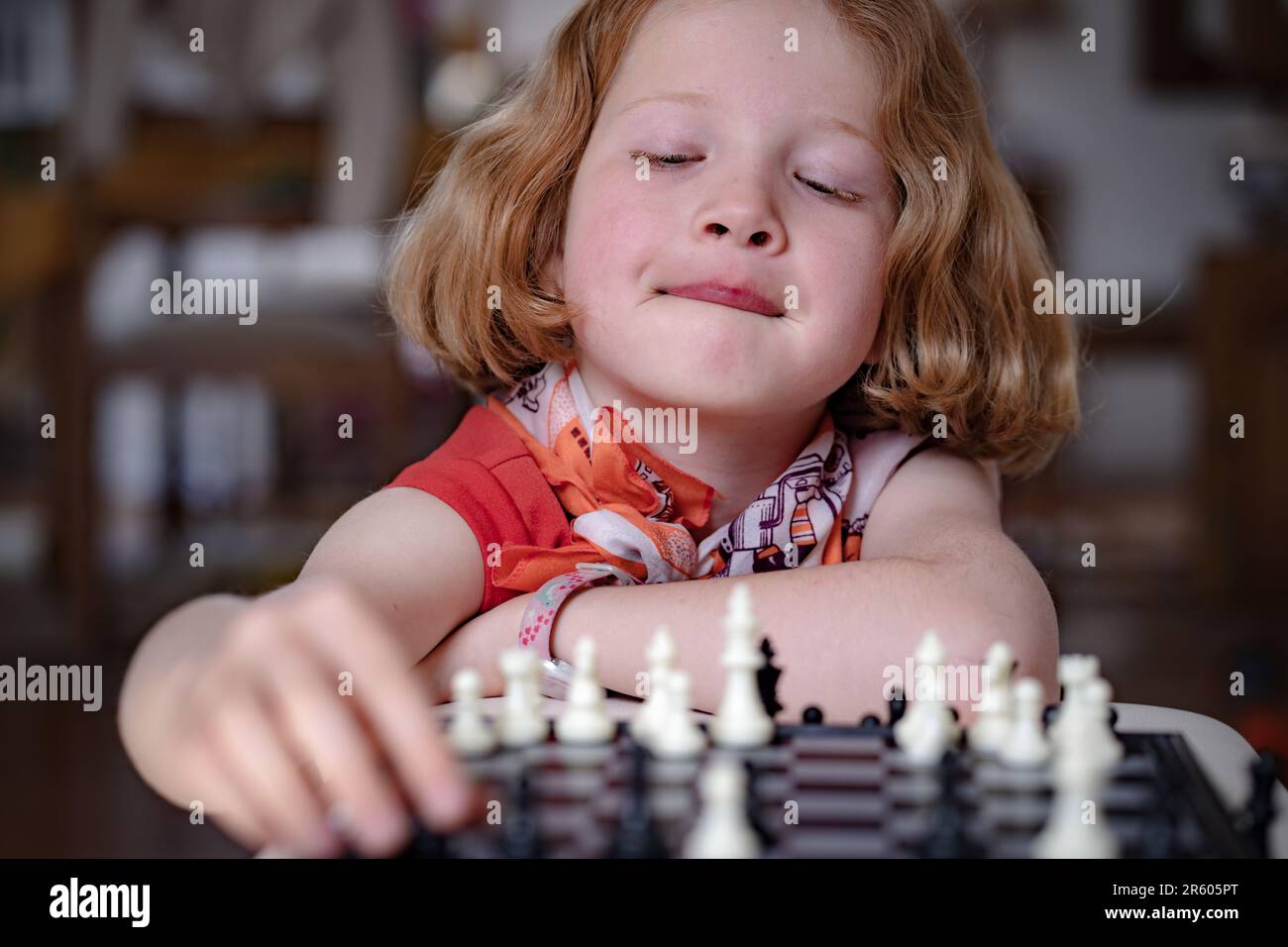 A red- haired girl playing chess, thinking pondering the next move. Differential focus, close up. Stock Photo