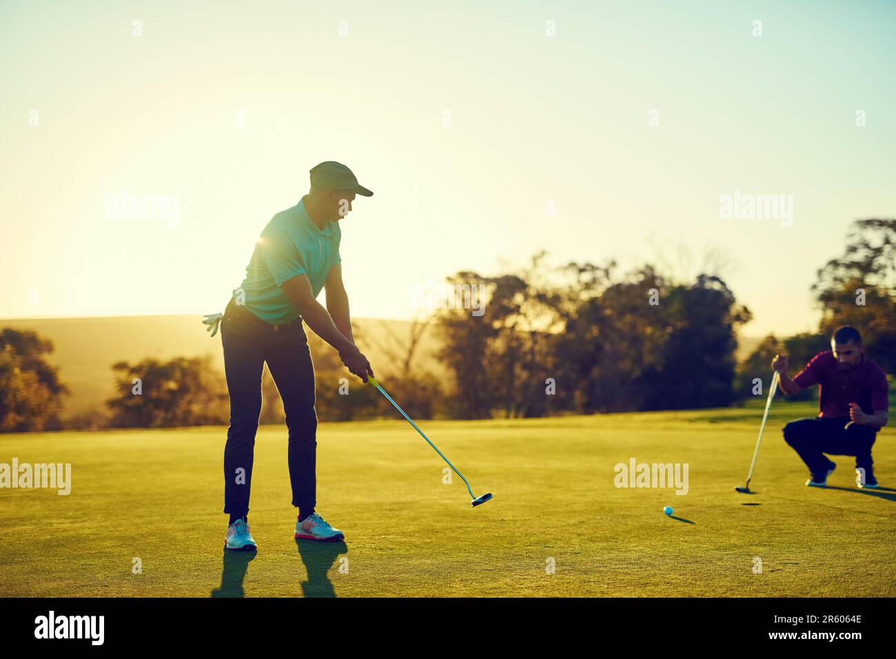 I hope my ball is not afraid of the dark. two friends playing a round of golf out on a golf course. Stock Photo