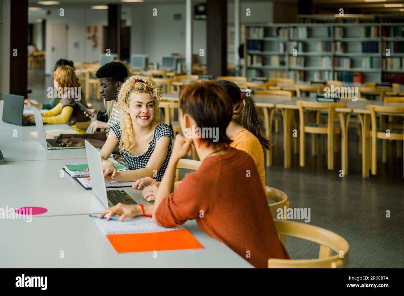 Group of multiethnic students sitting in library Stock Photo - Alamy