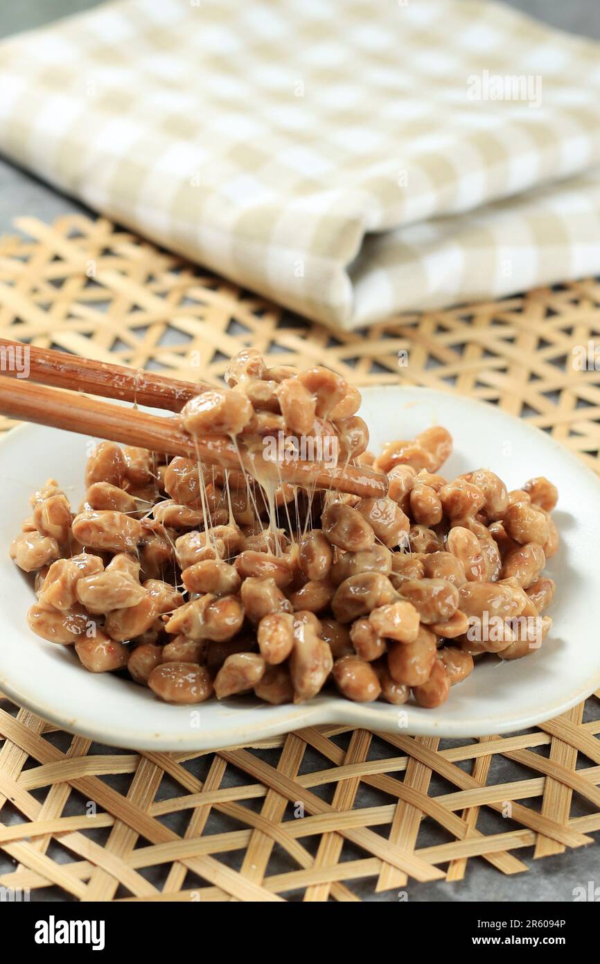 Close Up Natto Fermented Soybean with Stinky Smell. Japanese Healthy Traditional Food. Lift Natto with Chopstick. Selected Focus. Stock Photo