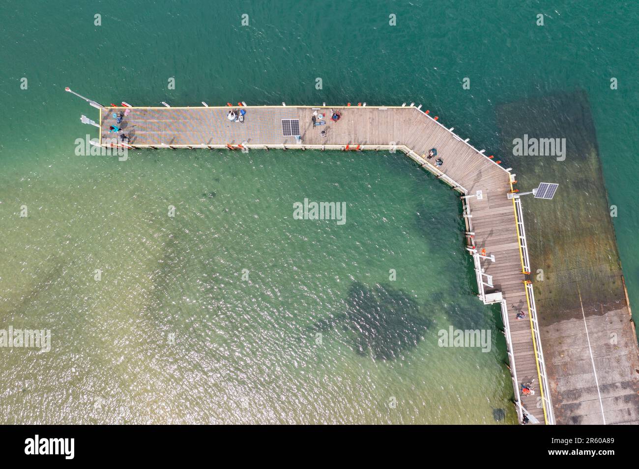 Aerial view of fisherman on a small jetty next to a boat ramp at