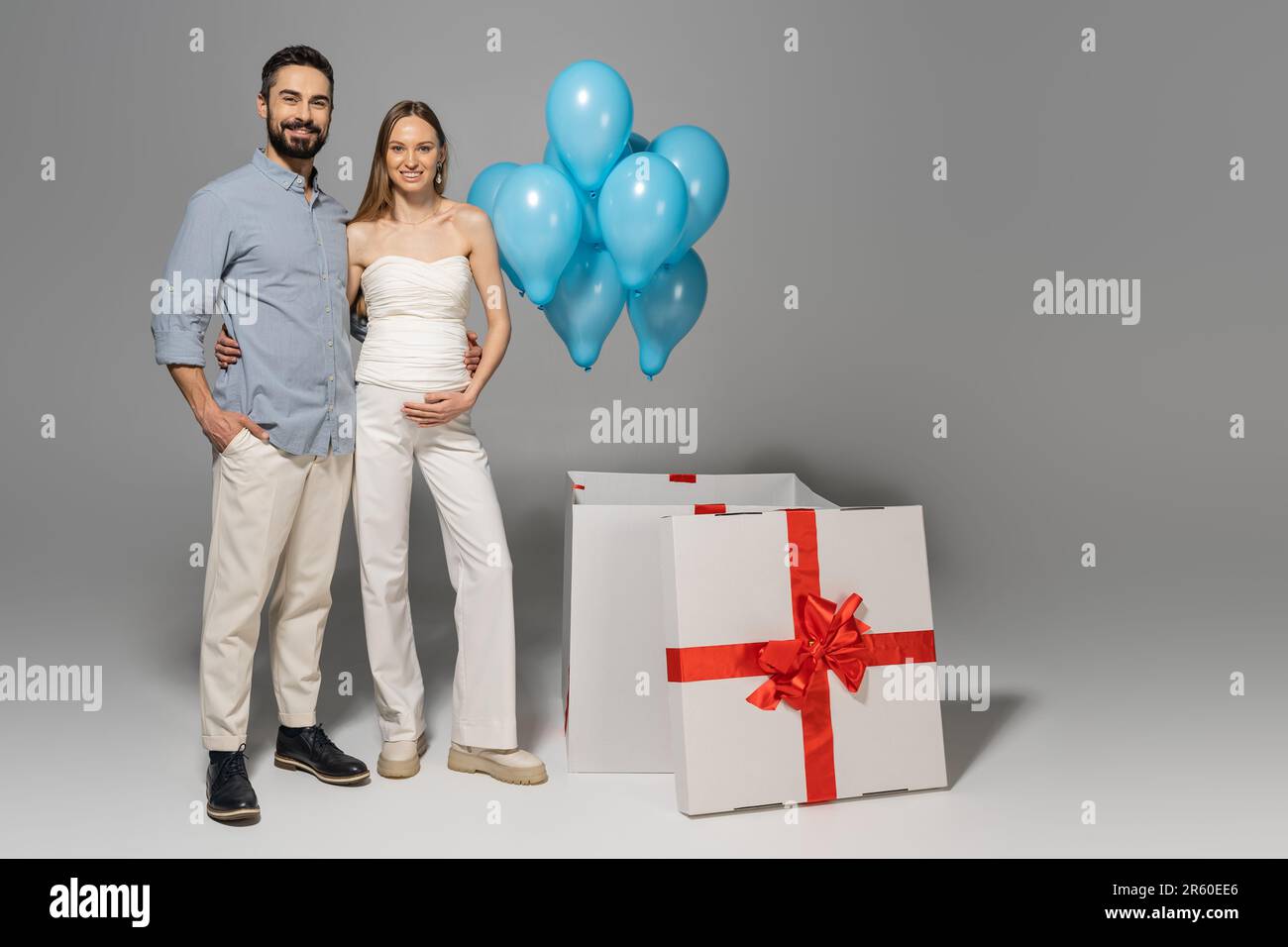 Hugging Balloons Full length of cheerful and trendy expecting parents hugging and ...