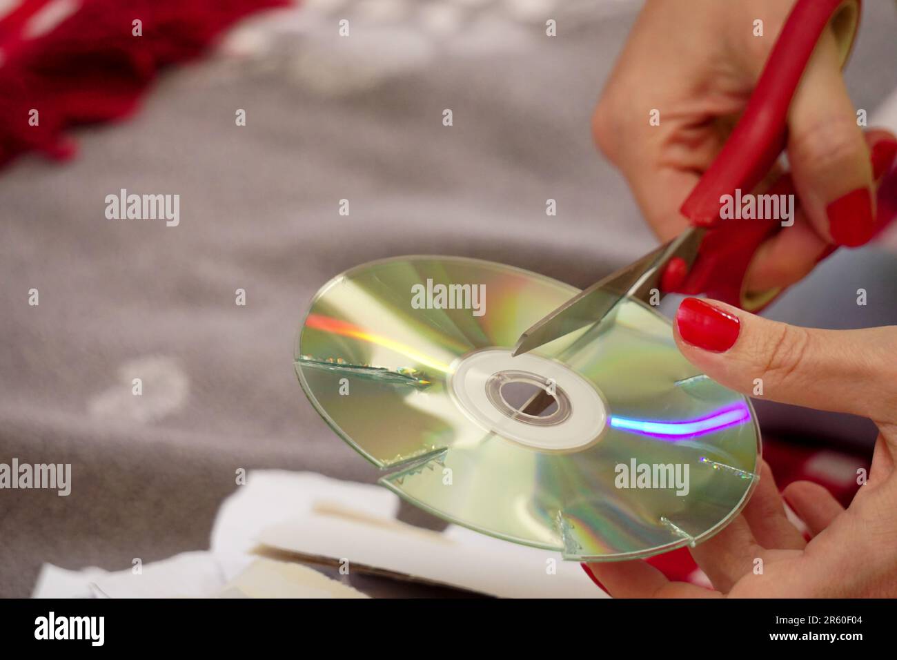 Woman cutting old compact discs with scissors at home close up view Stock Photo
