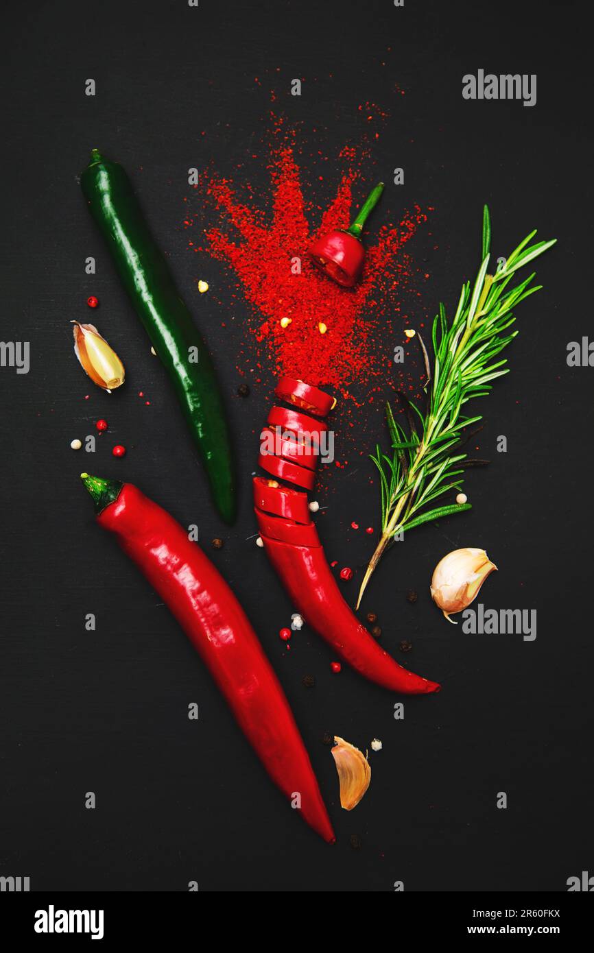 Paprika, exploding chili peppers, garlic and rosemary on a dark ...