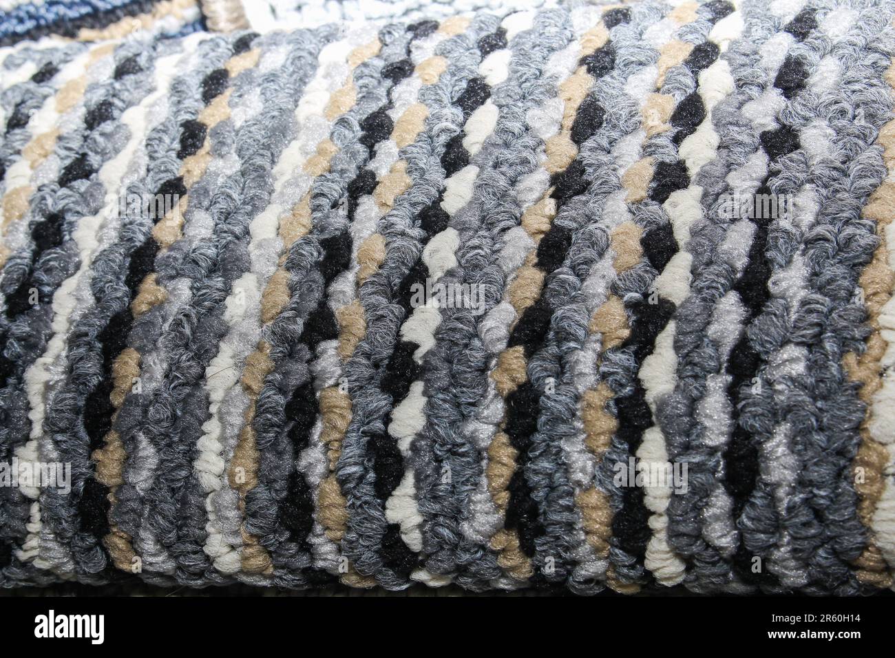 Close-up of a multi-colored striped carpet with thick woven loops. Features a vibrant mix  blue, grey, brown, and white tones. Stock Photo