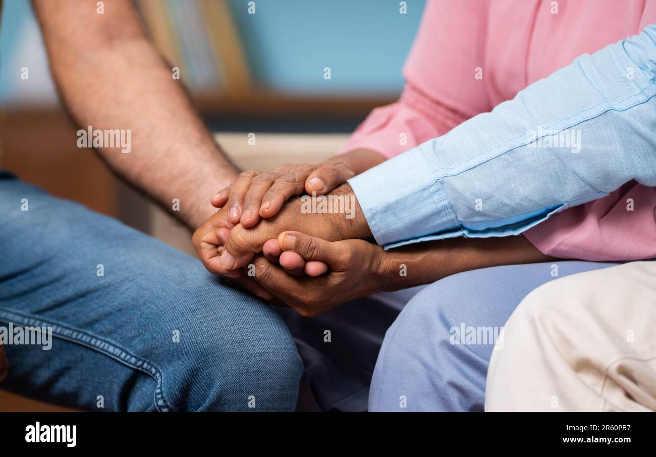 Close up shot of senior parents consoling to adult son by holding hands at home - concept of family support, togetherness and parenthood. Stock Photo