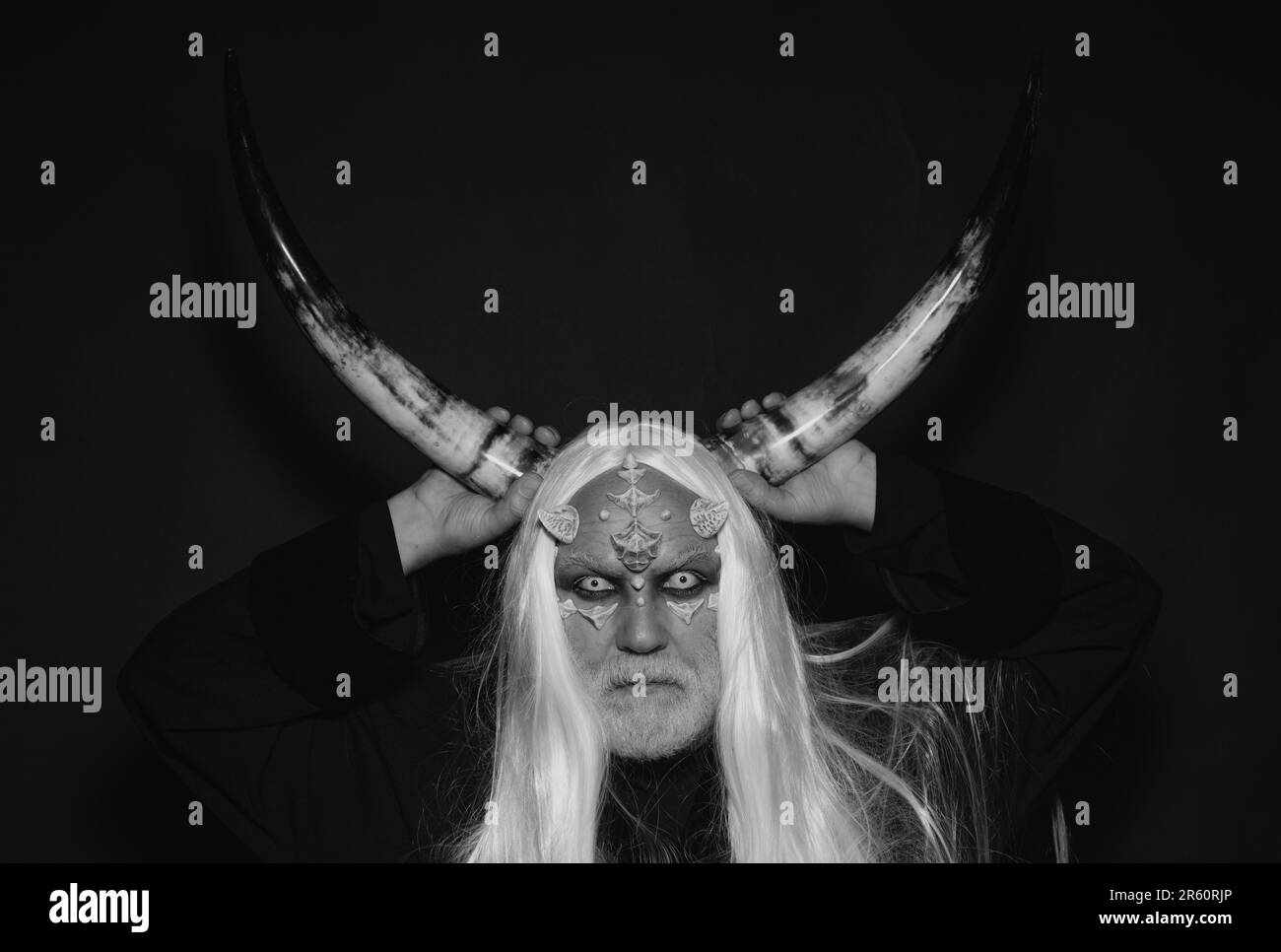 Horror with scary Halloween man. Viking with a horned head. Bearded old