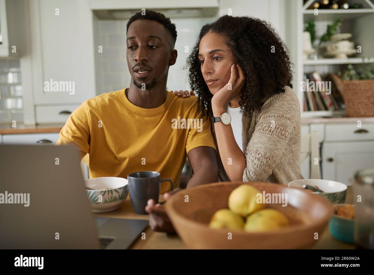 Young multiethnic couple using a laptop while having breakfast Stock Photo