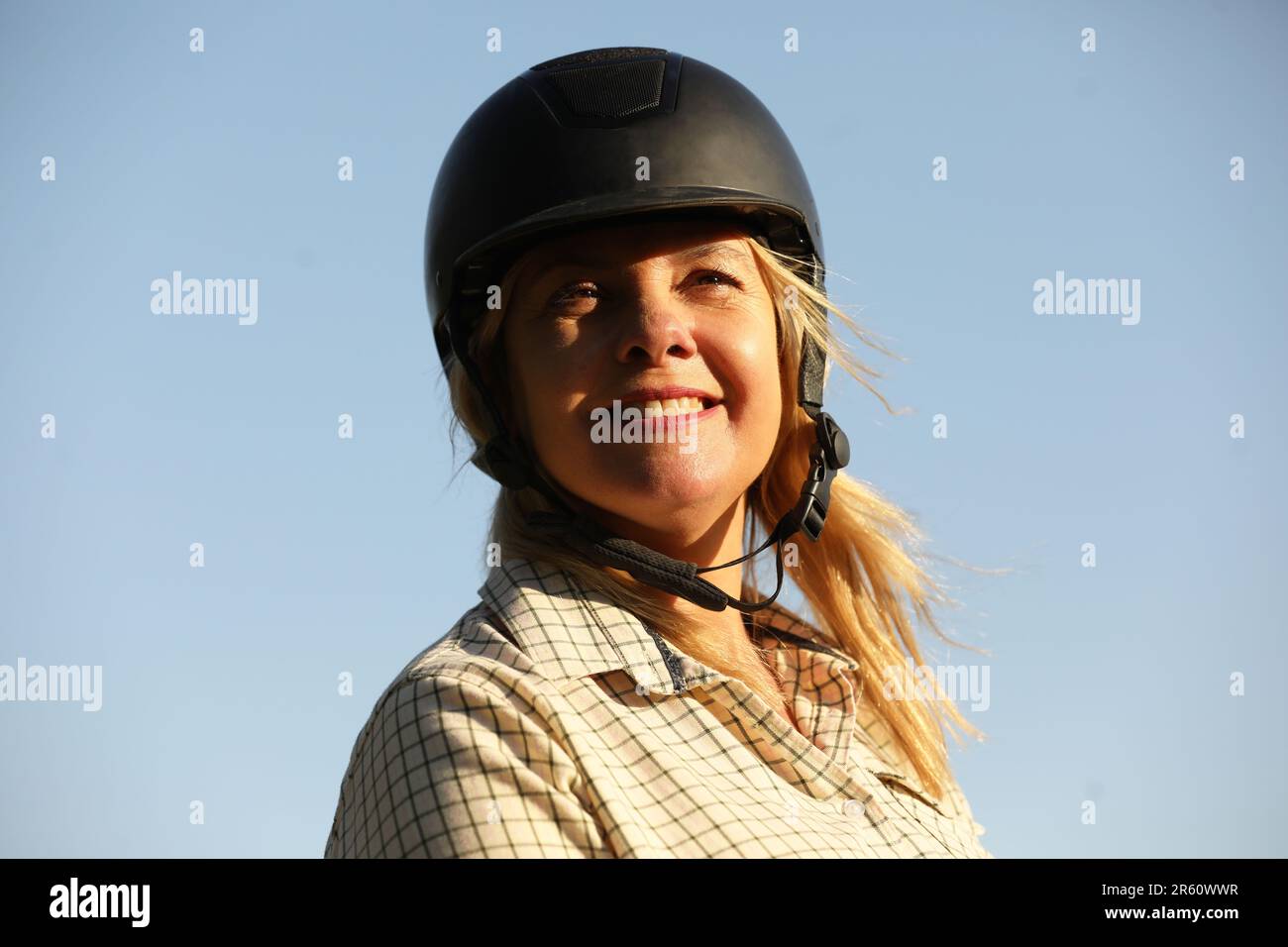 Closeup of a blonde woman wearing a riding hat, smiling Stock Photo