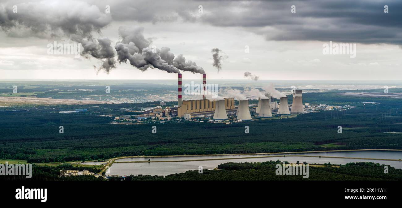 Aerial view of power plant, smoke from chimneys and open-cast coal mine in Belchatow under moody cloudy sky, Poland Stock Photo