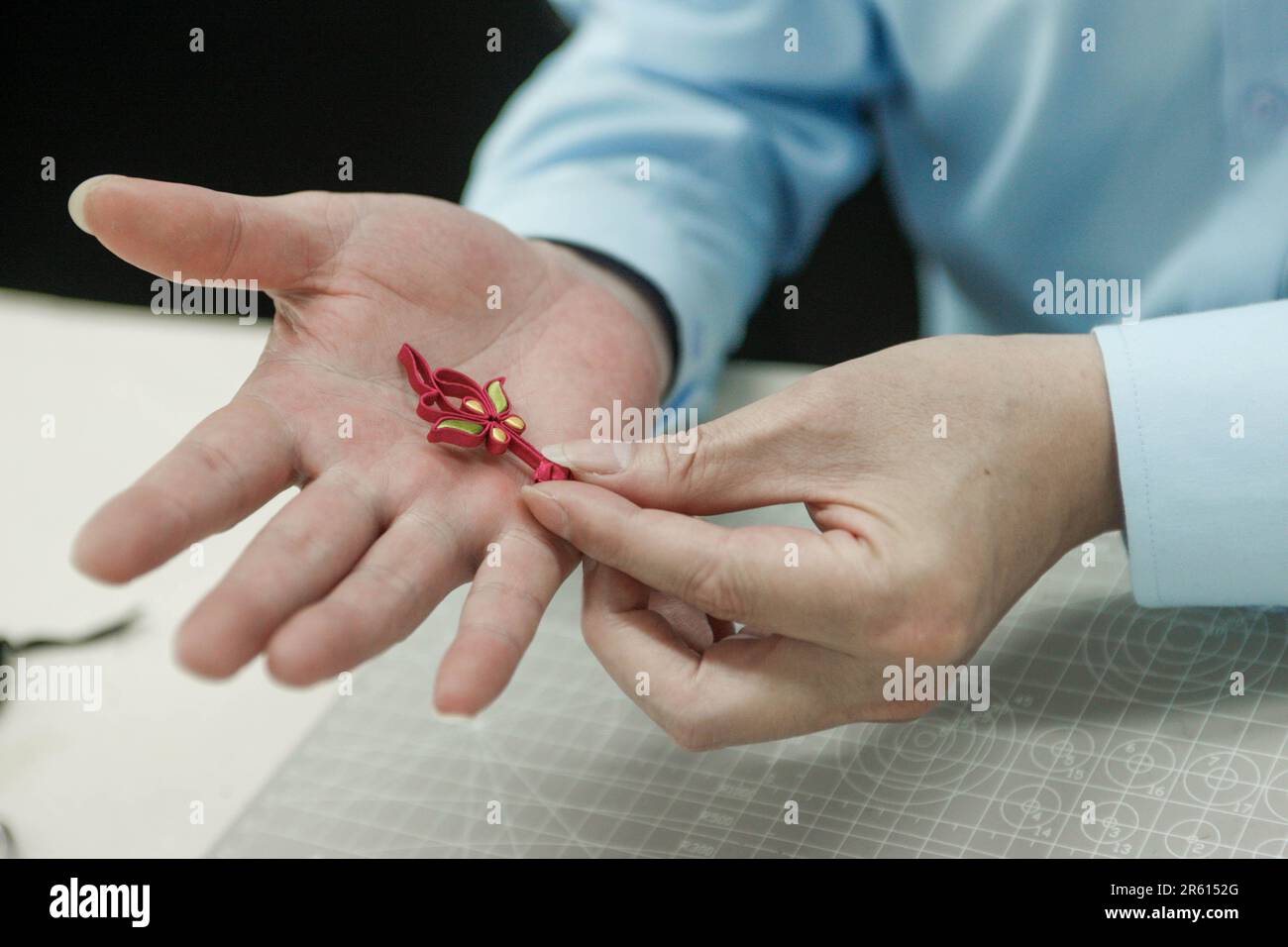 (230606) -- SHANGHAI, June 6, 2023 (Xinhua) -- Jiang Manzong shows a Pankou (knot button) at a training institute for Longfeng Cheongsam in Shanghai, east China, May 31, 2023. Cheongsam, or Qipao, is a traditional wearing of Chinese women which takes inspiration from the ethnic clothing of Manchu people. Evolving with the time, it nowadays represents a new fashion for Chinese women who value the tradition and elegance.  As a representative of Shanghai-style cheongsam which emphasizes the beauty of woman's curve, the Longfeng cheongsam traces back to the reign of China's Qing Dynasty Emperor Qi Stock Photo