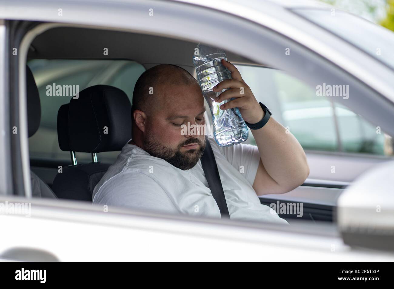 Weary overweight man drives car with broken air conditioner in hot