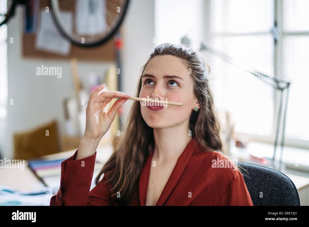 Portrait of funny woman with pencil in mouth, having fun at work. Stock Photo