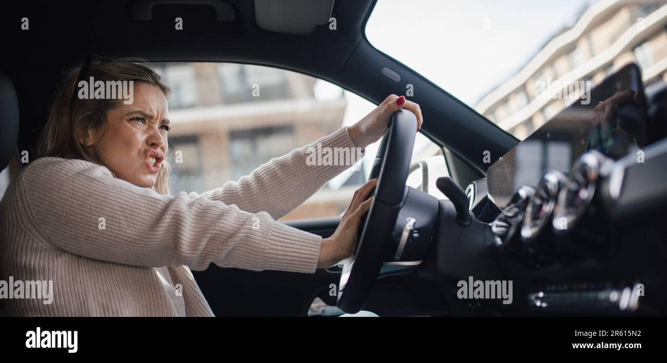 Upset woman driving her car in a city. Stock Photo