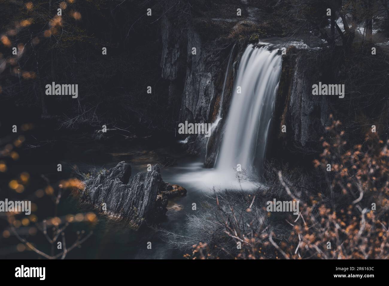 A scenic view of a lush tropical waterfall cascading down a rocky cliff ...