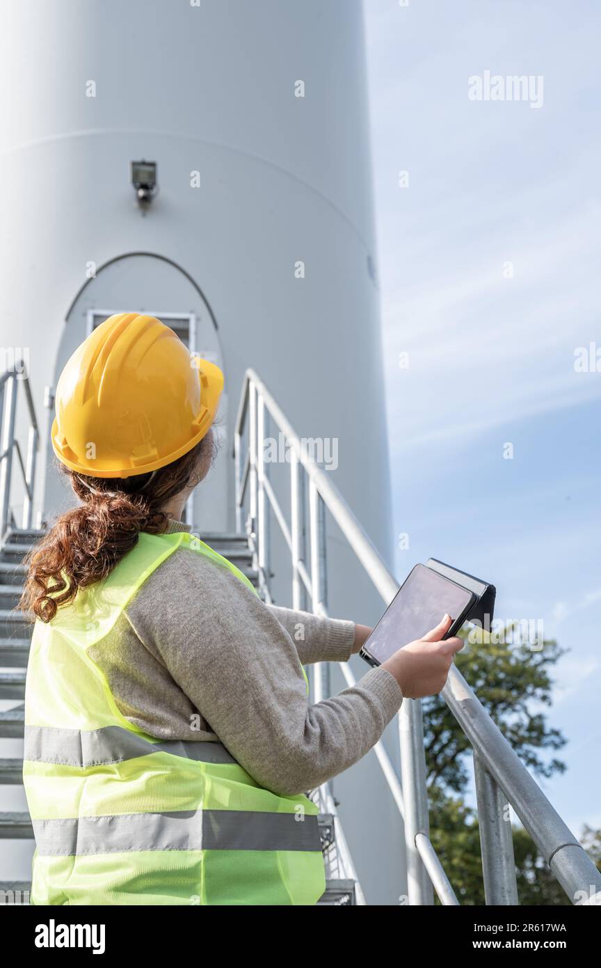 A female engineer using a tablet while wearing protective gear and a hard hat. Stock Photo