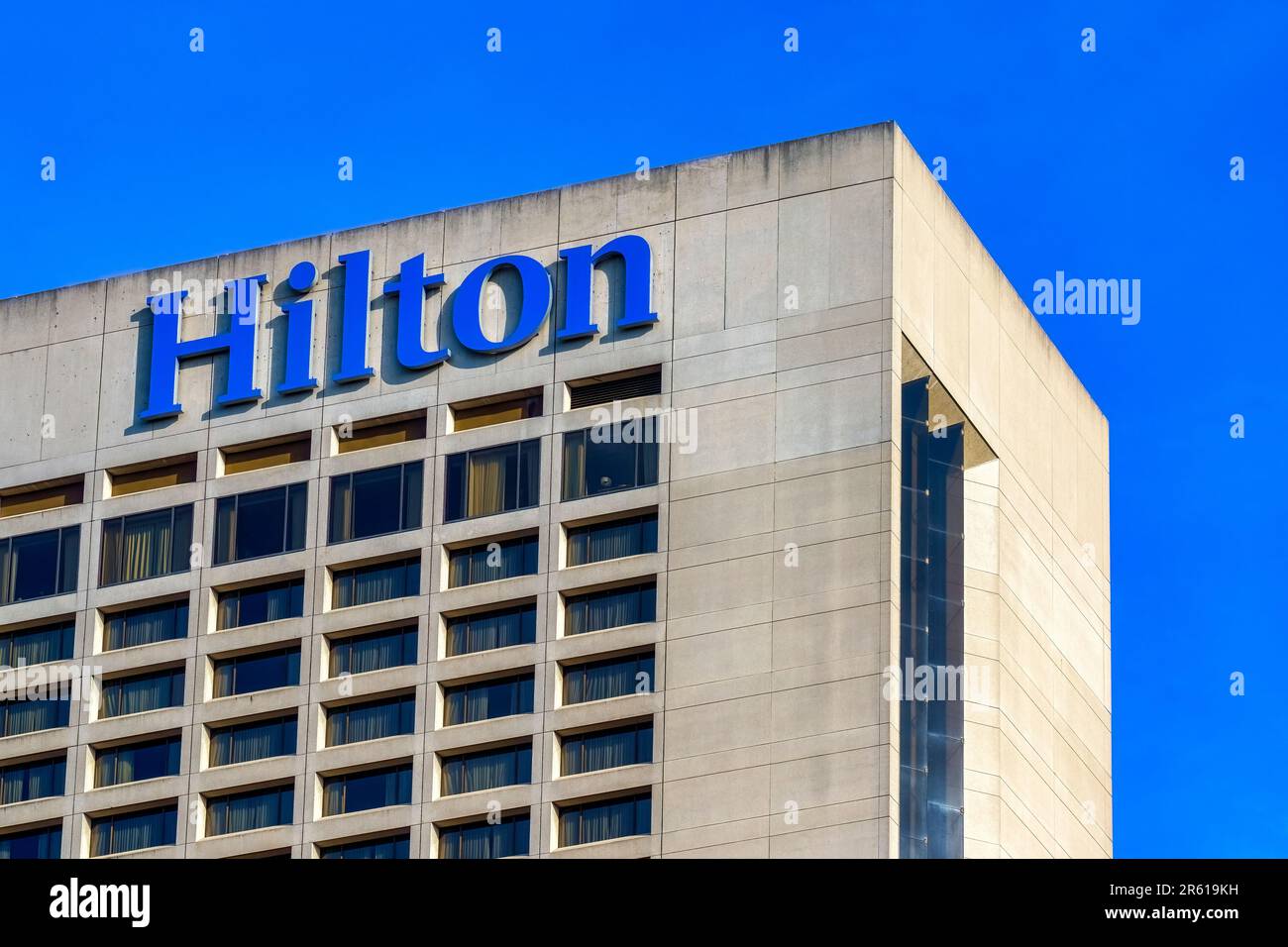Toronto, Canada - May 13, 2023: The top portion of a building displaying a bold 'Hilton' sign. The building has glass windows; no people are in the sc Stock Photo