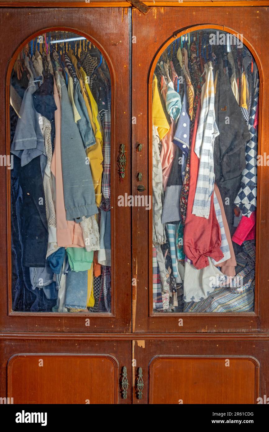Clothes hang on hangers in an old wardrobe Stock Photo