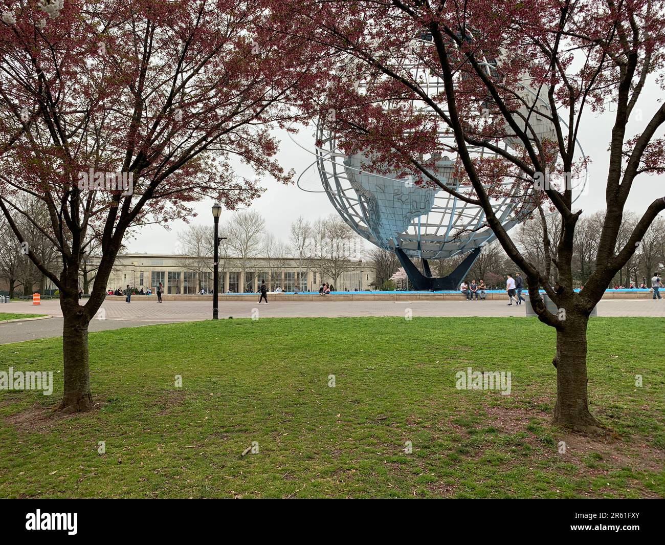 Cherry blossoms frame the Unisphere, a stainless steel metal globe in Flushing Meadows Corona Park, home to the New York Worlds Fair Stock Photo