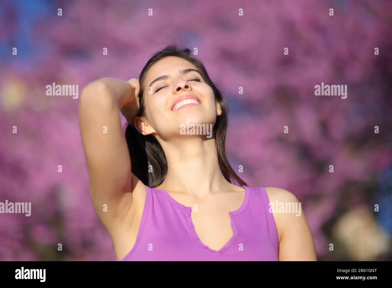 Happy woman smiling and touching hair in a violet park Stock Photo
