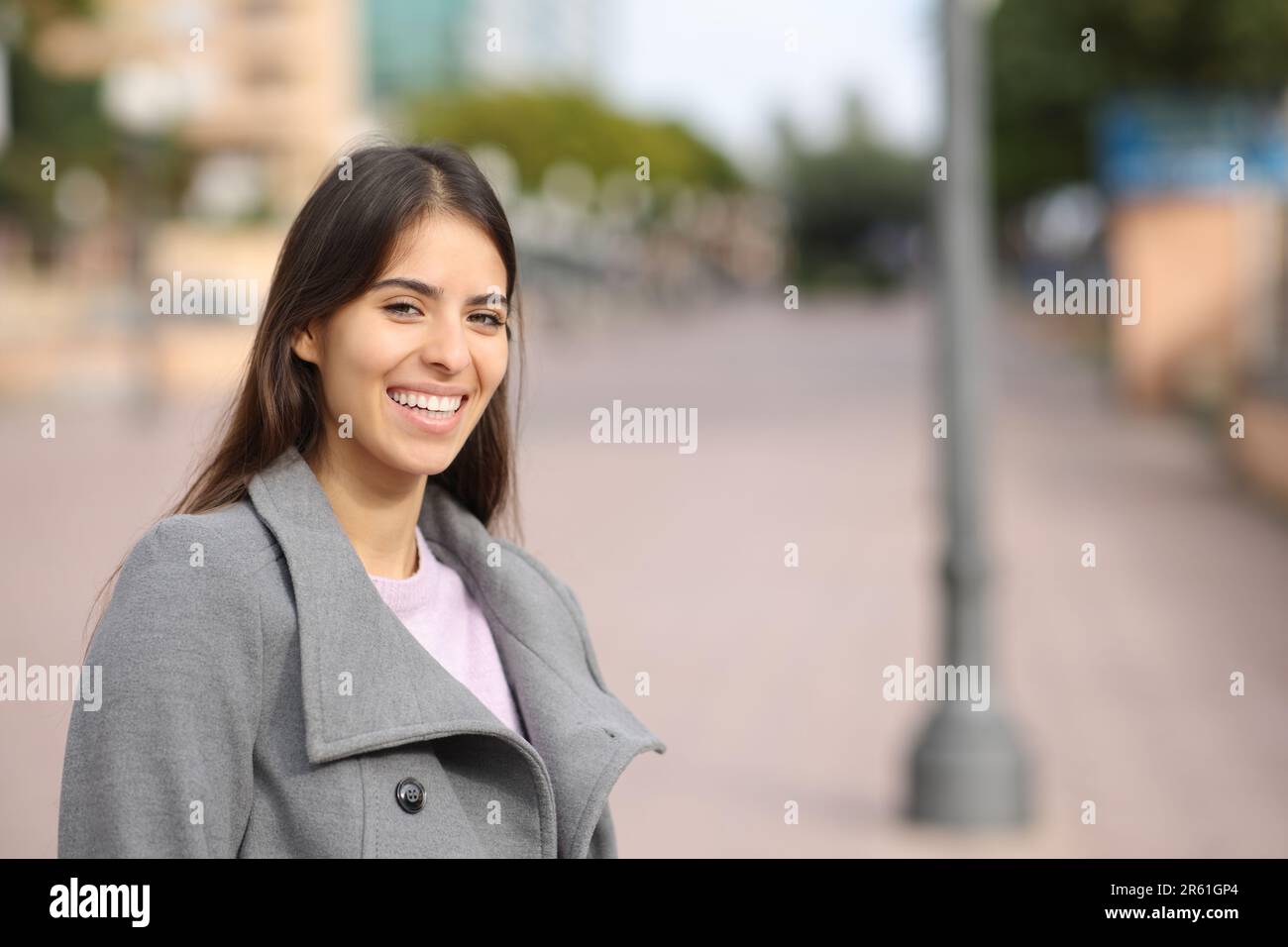 Happy woman in winter laughing standing in the street looks at you Stock Photo