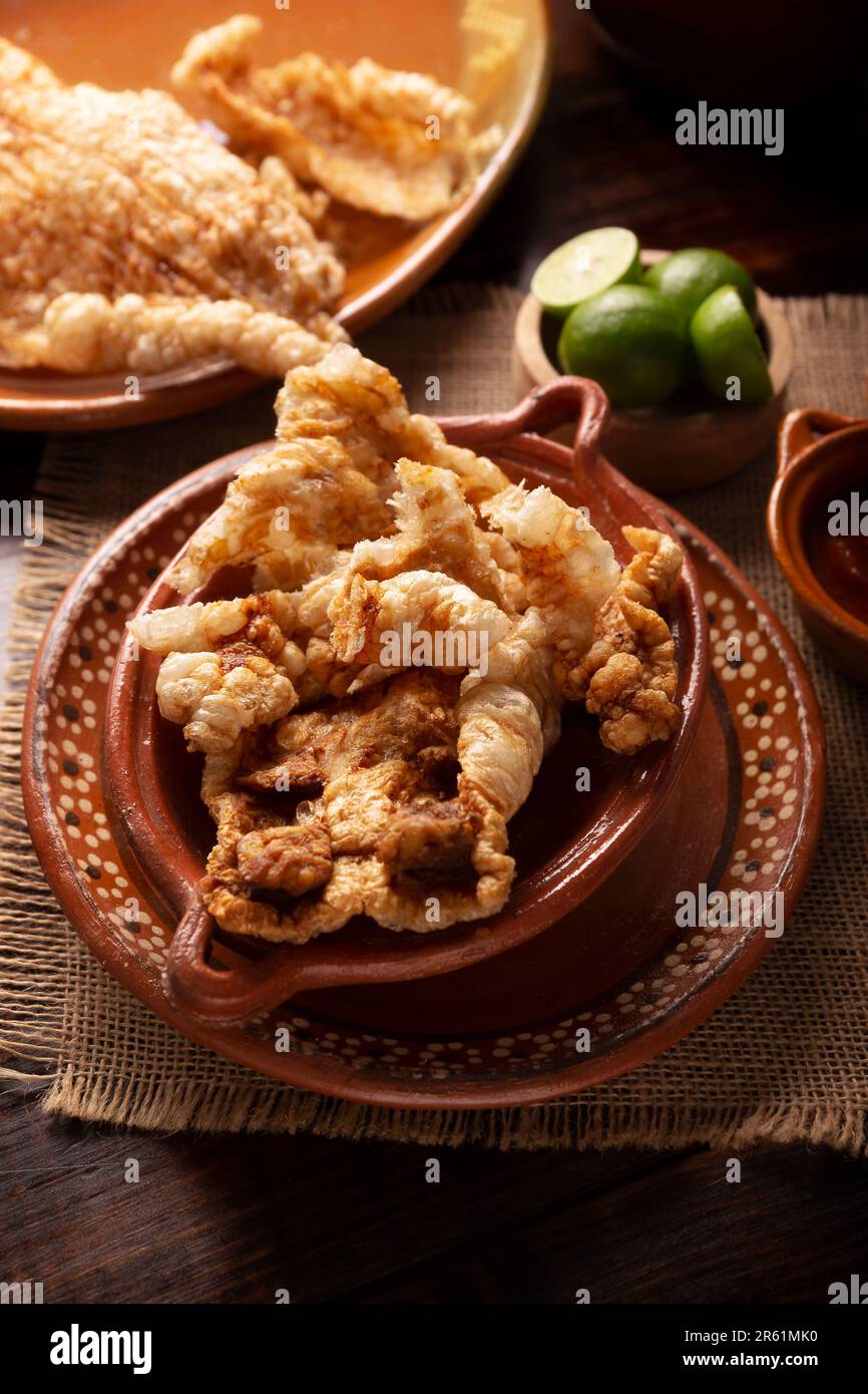 Chicharron. Crispy Fried pork rind, are pieces of aired and fried pork skin, traditional Mexican ingredient or snack served with lime juice and red ho Stock Photo