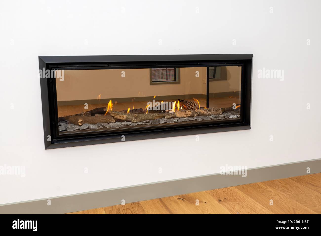 A modern double sided fireplace burning brightly with a warm, orange flame Stock Photo