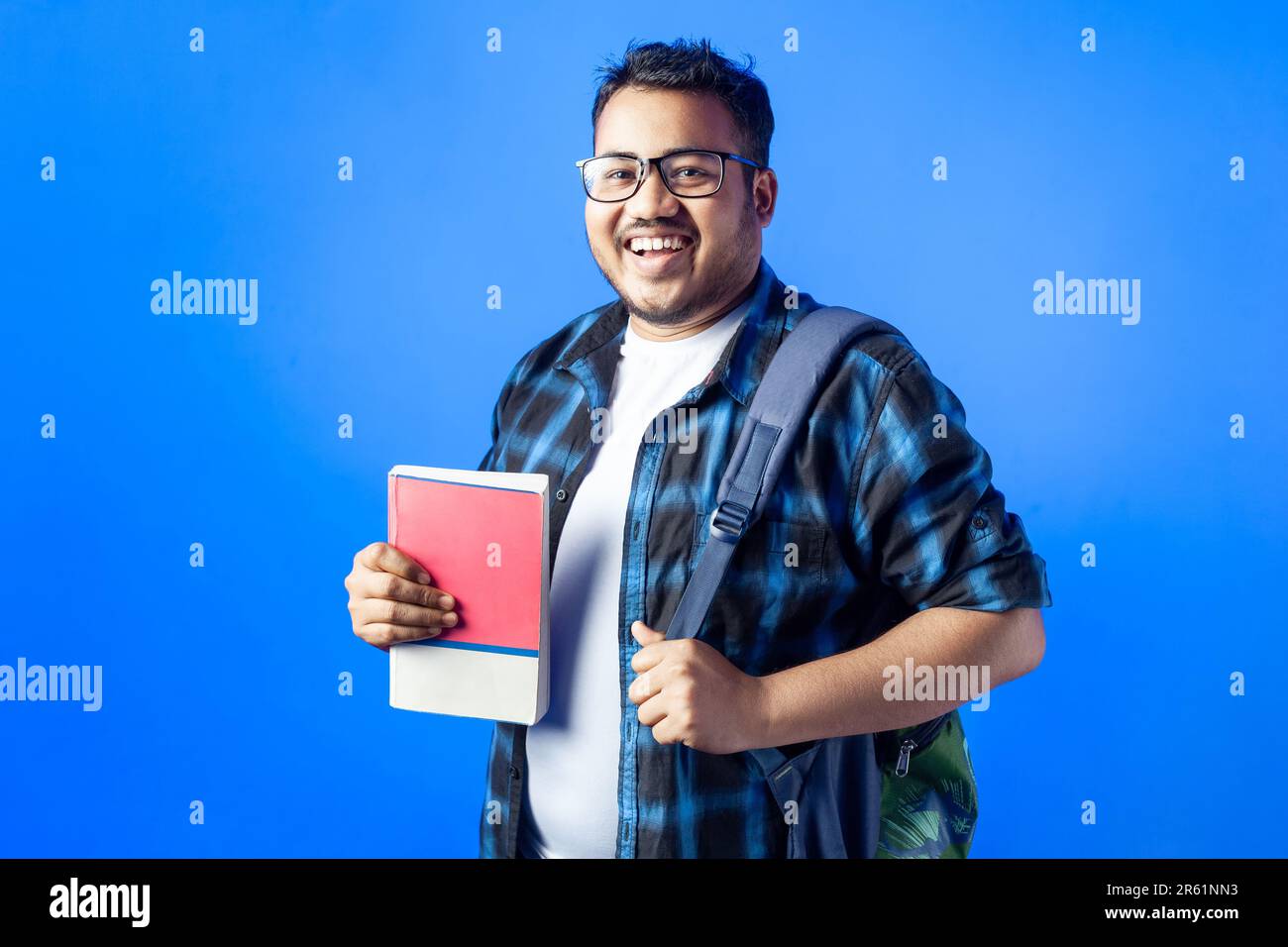 One young Indian student holding books and backpack and laughing ...