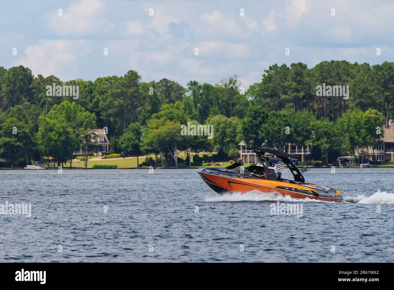 Boater on orange wakeboard ski boat enjoying summer day on the lake. Stock Photo