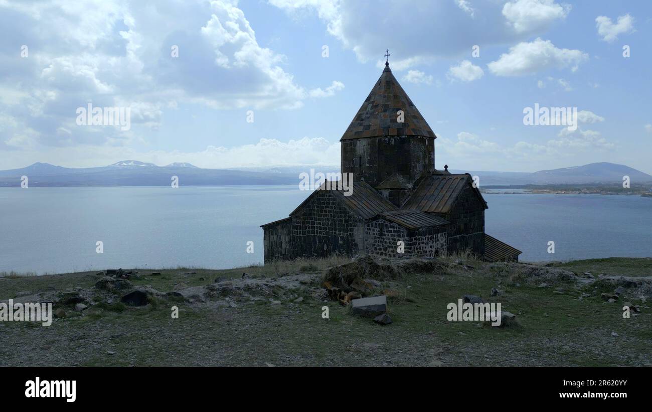 Sevanank Monastery Complex in Armenia. The monastery building with the cross is seen from behind, against the background of Lake Sevan, the high snowy Stock Photo