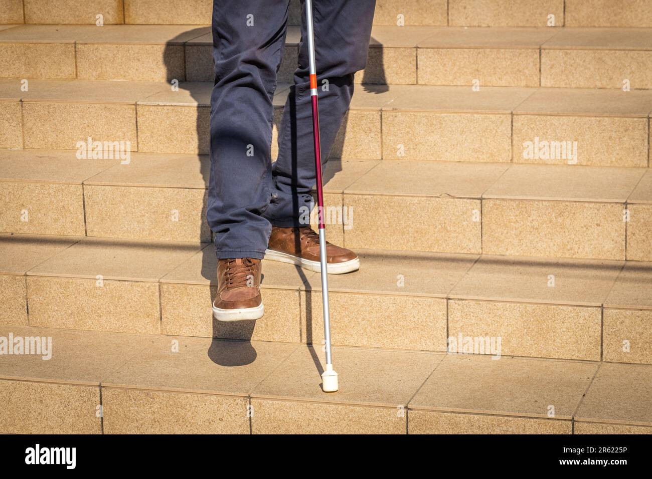 a blind person tries to go down the stairs helping himself with a cane