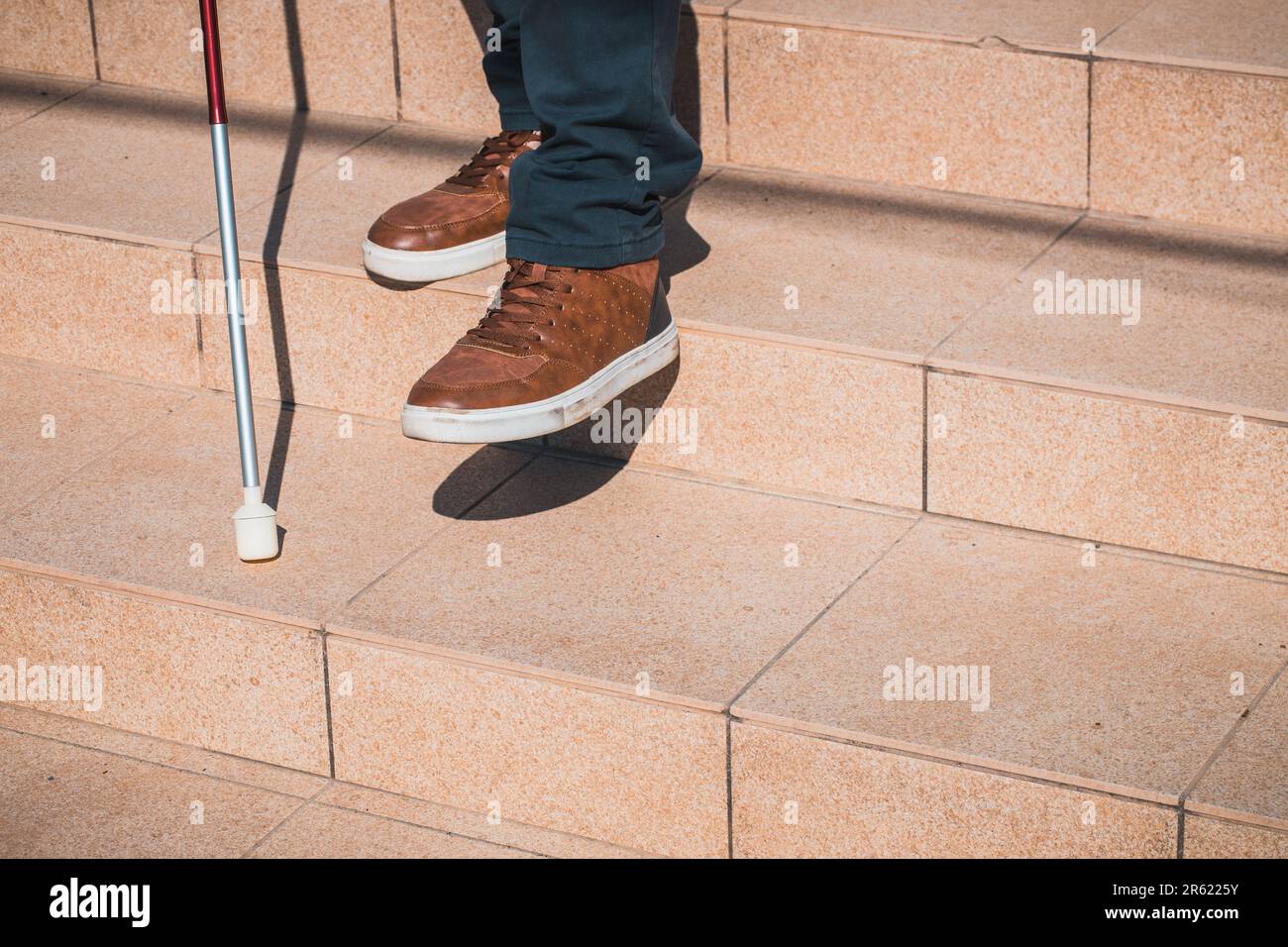 a blind person tries to go down the stairs helping himself with a cane