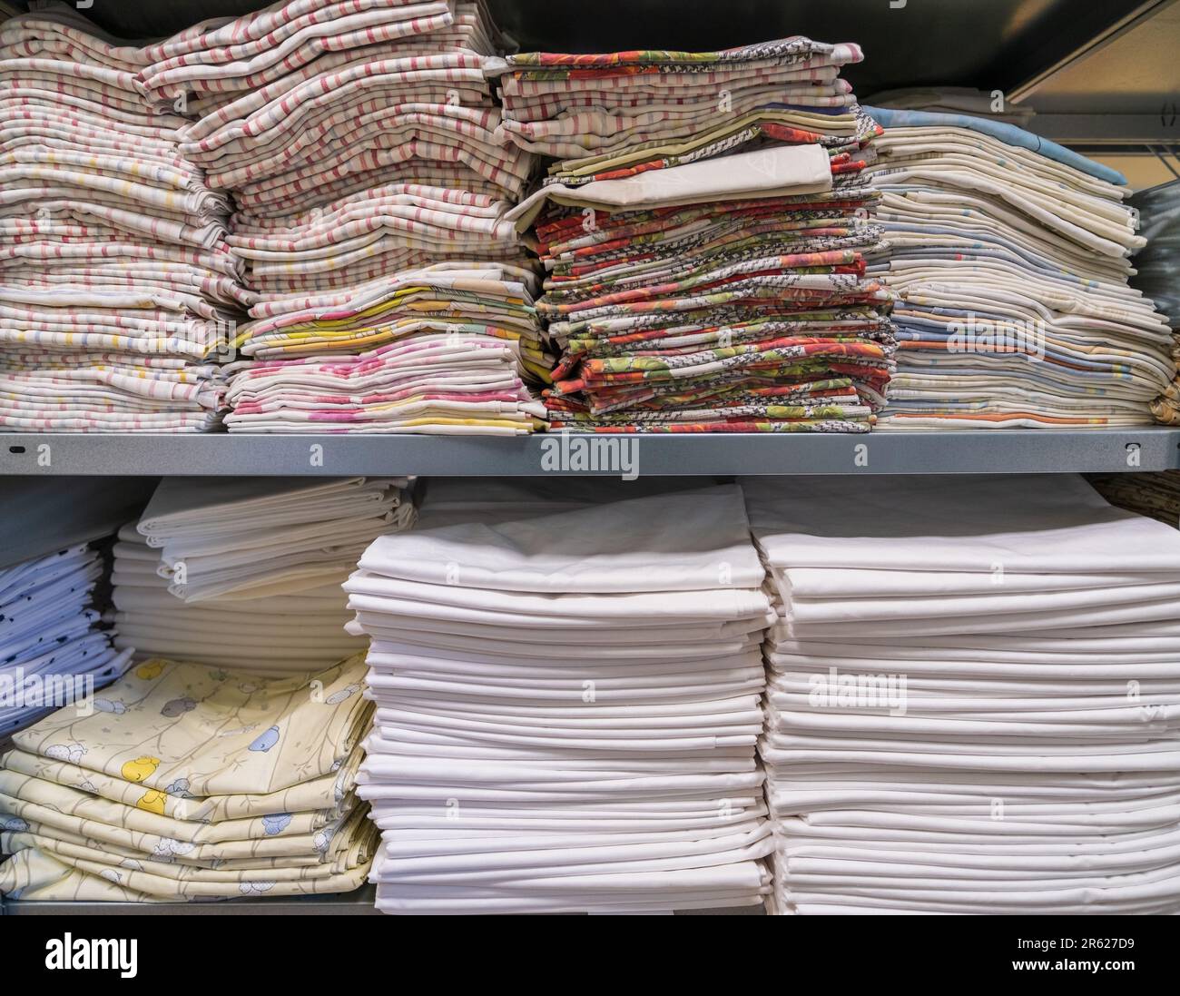 A pile of folded clean sheets or fabrics in an industrial laundry. Services for hotels, hospitals, clinics and companies Stock Photo