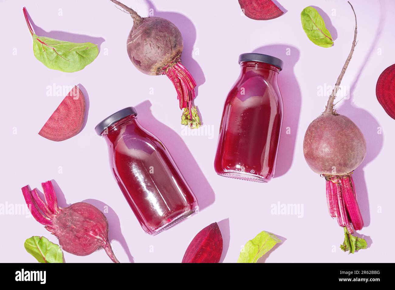 Bottles of healthy beet juice and spinach on lilac background Stock