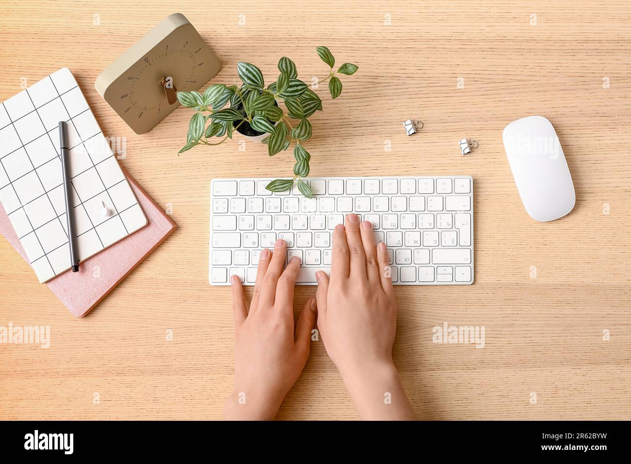 Female programmer using computer keyboard with clock and mouse on wooden background Stock Photo
