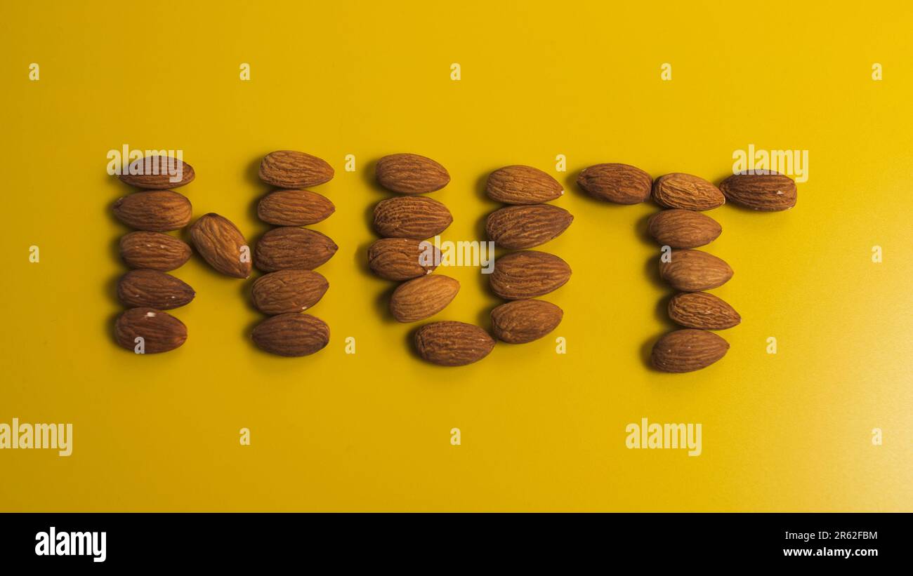 Inscription nut from almond grains on a yellow background Stock Photo